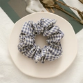 Detail shot of a blue and white checkered fabric scrunchie on a decorative white plate - Deep Blue Plaid