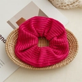 Detail of soft chunky rose pink knitted scrunchie with rib texture on wooden tray - Rose Red