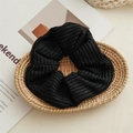 Close-up of a large black knit hair scrunchie with a thick ribbed texture on a tray - Black