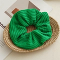 Detailed macro view of the bright green knitted texture on this large elastic scrunchie - Green