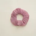 Close-up of pink pleated fabric scrunchie with metallic sheen and elastic texture - Pleated Pink