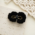Detail of hand-woven black knit bow hair clip with gold thread center on stone surface - Black Gold Thread