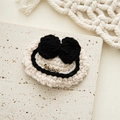 Detailed macro of handmade crochet hair clip featuring a bronze metal charm with text - White with Black Bow