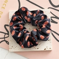 Detailansicht eines Samt-Scrunchies mit Football-Muster auf Steinhintergrund - Schwarz