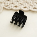 Detailed close-up of a matte black shark hair claw clip on a soft cream woven backdrop - Black