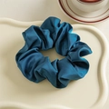Détail d'un chouchou en satin bleu marine élégant posé sur un plateau décoratif - Bleu marine