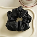 Détail d'un chouchou en satin noir élégant sur un plateau avec une tasse de thé - Noir