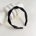 Close-up of black fabric twisted headband with non-slip teeth on a white display - Black Twisted