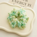 Detail eines grün-gelb karierten Haargummis aus strukturiertem Chiffon-Stoff - Grün