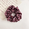 Makro-Detail des Satin-Haargummis mit Leopardenmuster, seidiger Textur und rosa Basis - Rosa Leopard