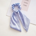 Close-up of light blue satin scrunchie with long ribbon bow showing silky fabric texture - Knotted Light Blue