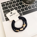 Drei hochelastische schwarze Haargummis mit matten goldenen Schnallen auf einem Laptop - Schwarz