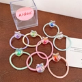Close-up of colorful elastic hair ties with iridescent peach-shaped beads on wood surface - Peach Style