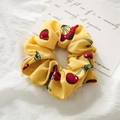 Detailed close-up of yellow scrunchie with red cherry pattern on soft fabric - Yellow Cherry