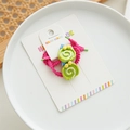 Detailed view of handmade pink elastic hair tie with green swirl charms on a white card - Avocado