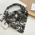Detail van zwart-witte paisley chiffon hoofddoek met elastische band op houten dienblad - Groot Paisley Wit