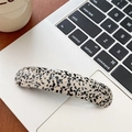 Detailansicht der gepunkteten Acetat-Haarspange auf einer Laptop-Tastatur am Arbeitsplatz - Gepunktetes Muster