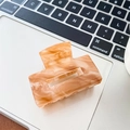 Primo piano di un fermaglio per capelli in acetato marmorizzato su una tastiera laptop - Caffè Sfumato