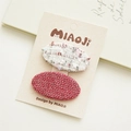 Détail de deux barrettes à cheveux ovales en tweed texturé rose et blanc sur carte cadeau - Tissé Blanc Rouge