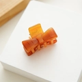 Close-up of small amber acetate bow hair claw clip with smooth polished finish - Amber
