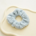 Dettaglio dell'elastico per capelli in pile teddy azzurro su vassoio decorativo - Velluto Teddy Blu