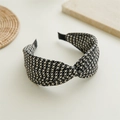 Detail view of houndstooth knot headband on a decorative stone base for hair accessory - Cross Houndstooth Light Coffee