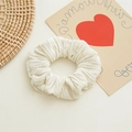 Gros plan d'un chouchou plissé en velours beige montrant la texture douce du tissu - Blanc Cassé