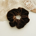Nahaufnahme eines eleganten braunen Samt-Scrunchies mit weichen Falten und Glanzeffekt - Braun
