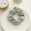 Nahaufnahme von geblümtem Baumwoll-Scrunchie in Blau mit rosa Mustern auf Keramikteller - Blauer Hintergrund Rosa Floral (Baumwolle C)