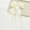 Detaillierte Nahaufnahme der cremeweißen Satin-Schleife mit langen, eleganten Bändern - Streamer Schleife Haarspange / Langes Cremegelb
