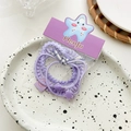 Detailed view of purple elastic hair ties set with plaid bow and heart charms on a plate - Purple