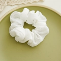 Detalle de scrunchie blanco a cuadros con lentejuelas sobre un plato verde - Estilo de Cuadrícula de Lentejuelas Blancas