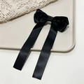 Close-up of elegant black satin bow hair clip with long ribbons on a beige tray - Black