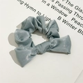 Detail van de glanzende satijnen textuur en de strik van de grijsblauwe scrunchie - Groen