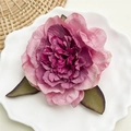 Detailaufnahme einer rosa Pfingstrosen-Haarklammer mit geschichteten Blüten und Blättern - Pfingstrose Bohnenpastenrot