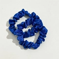 Close-up of two deep blue satin scrunchies with elastic pleats and silk-like sheen - Blue