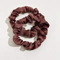 Close-up of two chocolate brown satin hair scrunchies with elegant silky texture and pleats - Brown