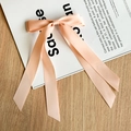 Detail der pfirsichfarbenen Satin-Schleife mit langen Bändern auf Holzoberfläche - Rosa
