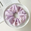 Close-up of a tie-dye purple and white cotton scrunchie on a white ceramic plate - Purple