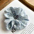 Detailansicht eines hellblauen Haargummis mit weißem Gänseblümchen-Blumenmuster - Blau