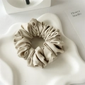 Close-up of beige satin scrunchie featuring high-density pleated texture on white tray - Light Gray