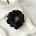 Detailed view of black satin pleated scrunchie with twill fabric texture on a white tray - Black