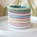 Close-up of 8-piece woven hair ties in macaron colors on a white ceramic plate - Pink Blue Green Palette
