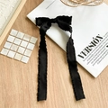 Detail einer eleganten schwarzen Haarklammer aus Plissee-Stoff mit langen Bändern auf Magazin - Schwarz