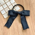 Detailed close-up of a black satin bow scrunchie with ruffled edges on a wooden table - Hair Tie Navy Pleated Bow