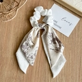 Detalle de coletero blanco con textura y cinta de flores vintage sobre superficie de madera - Doble Crema