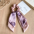 Detalle de coletero de satén rosa con lazo floral sobre superficie de madera clara - Doble Rosa Púrpura