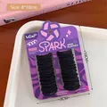 Detail von schwarzen Baby-Haargummis auf lila Karte präsentiert in einem weißen Tablett - Schwarz