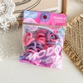 Detail of pink and purple seamless hair ties in a clear bag on white wood background - Style C