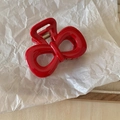 Detail der roten Schleife Haarklammer mit goldener Metallfeder auf weißem Papier - Kleine Schleife Rot